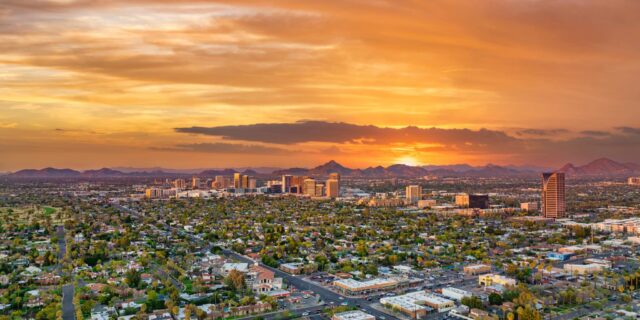 Aerial view of Greater Phoenix with mountains and a sunset in the background