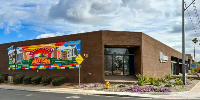 A large one-story office building with a colorful mural on the left side and Goodmans logo on the right.