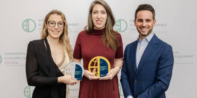 GPEC staff hold IEDC award plaques in front of backdrop