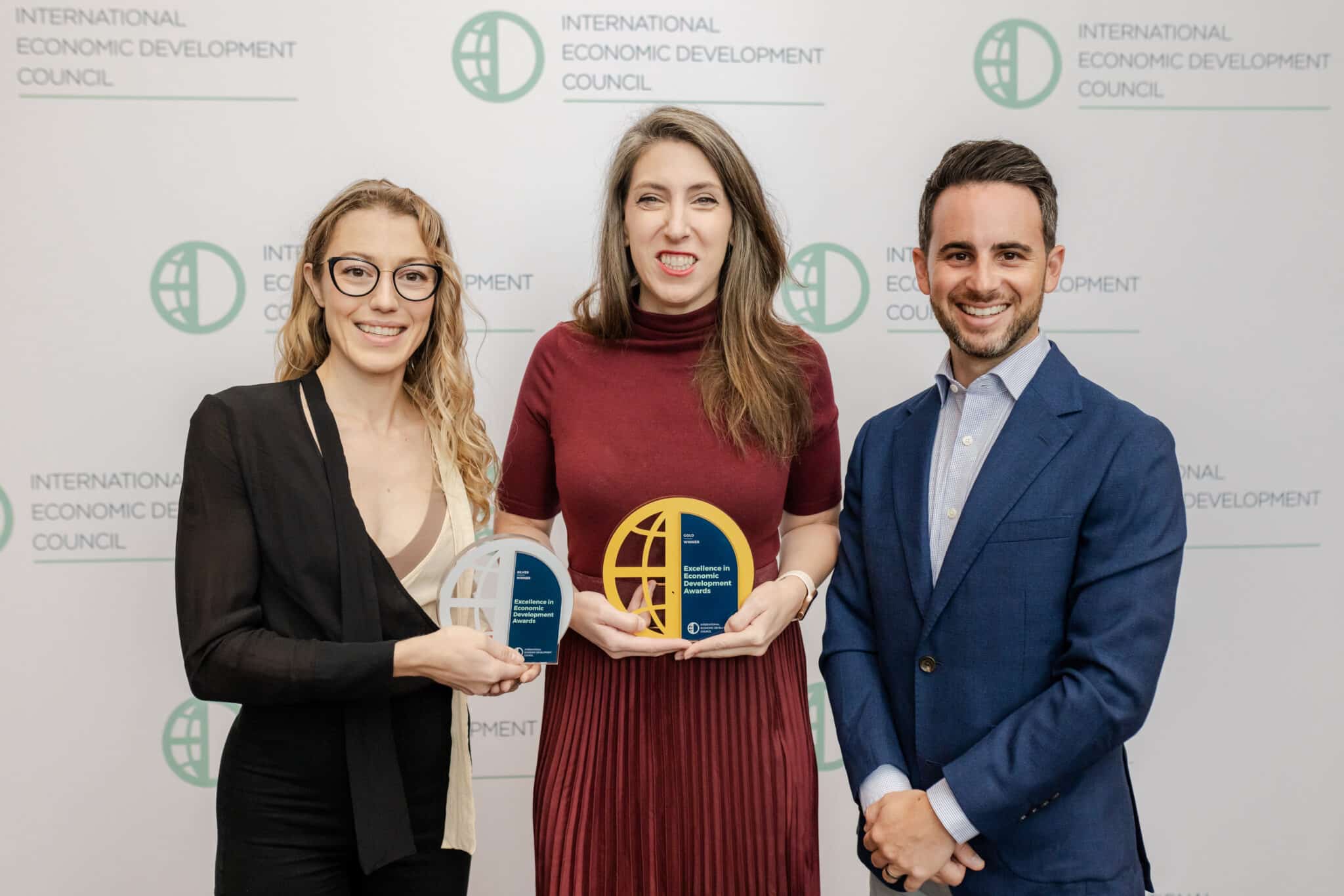 GPEC staff hold IEDC award plaques in front of backdrop