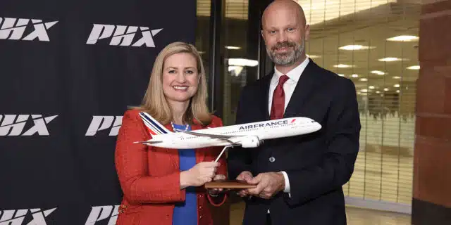 Kate Gallego (left) and Boaz Hulsman (right) hold a model replica of an Air France plane in front of a PHX Sky Harbor backdrop.