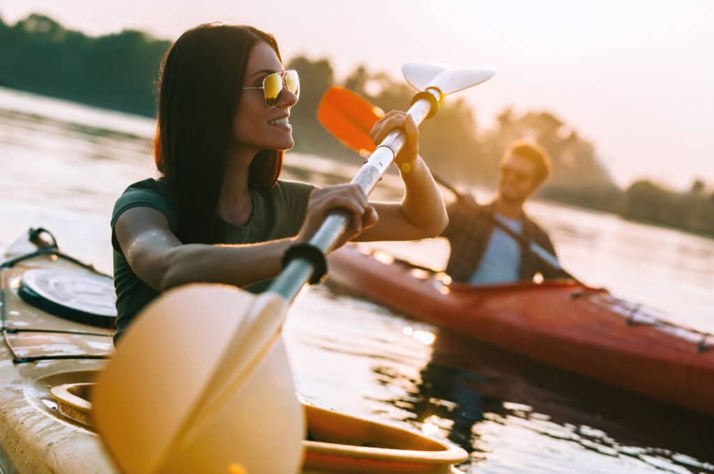 Young couple kayaking on river together and smiling